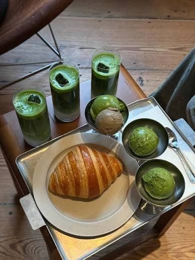 Three iced matchas, a croissant, and scoops of ice cream to share on a café table.